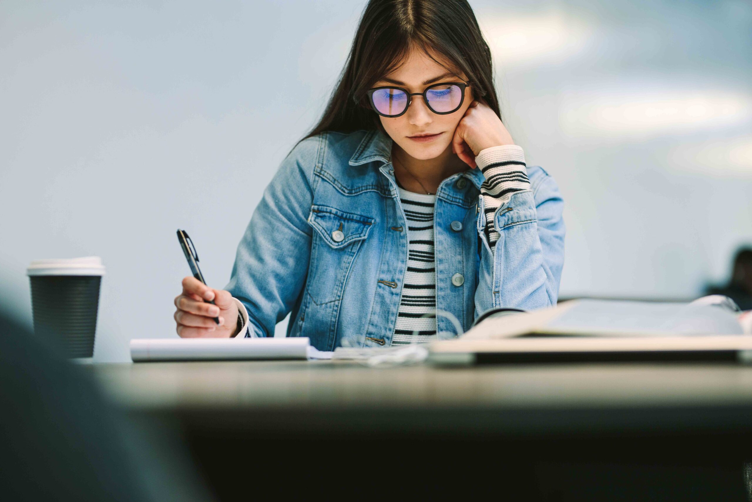 Female student sitting at college library and studying. Girl reading notes at college campus.