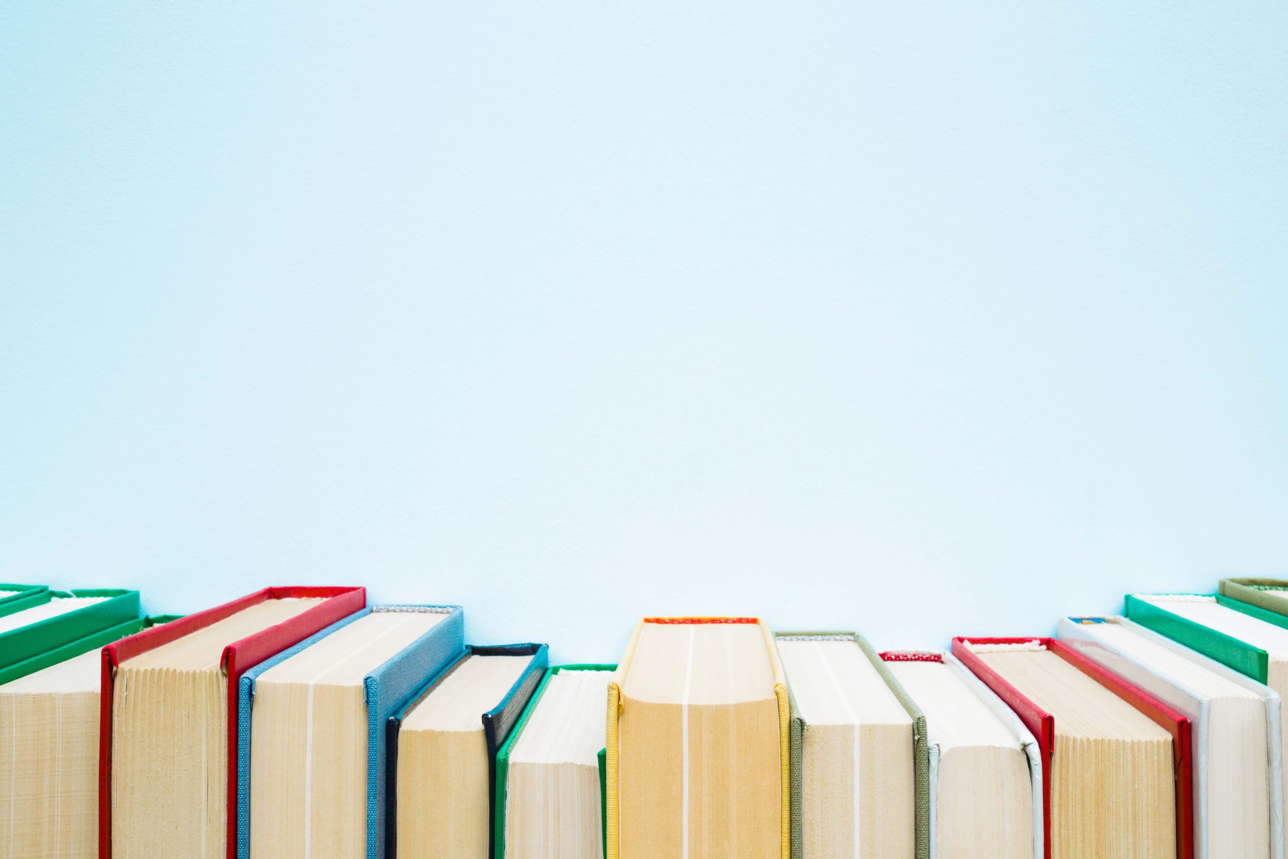 Row of old books with colorful covers on pastel blue background. Education concept. Mock up for different ideas. Empty place for text, quote or sayings.