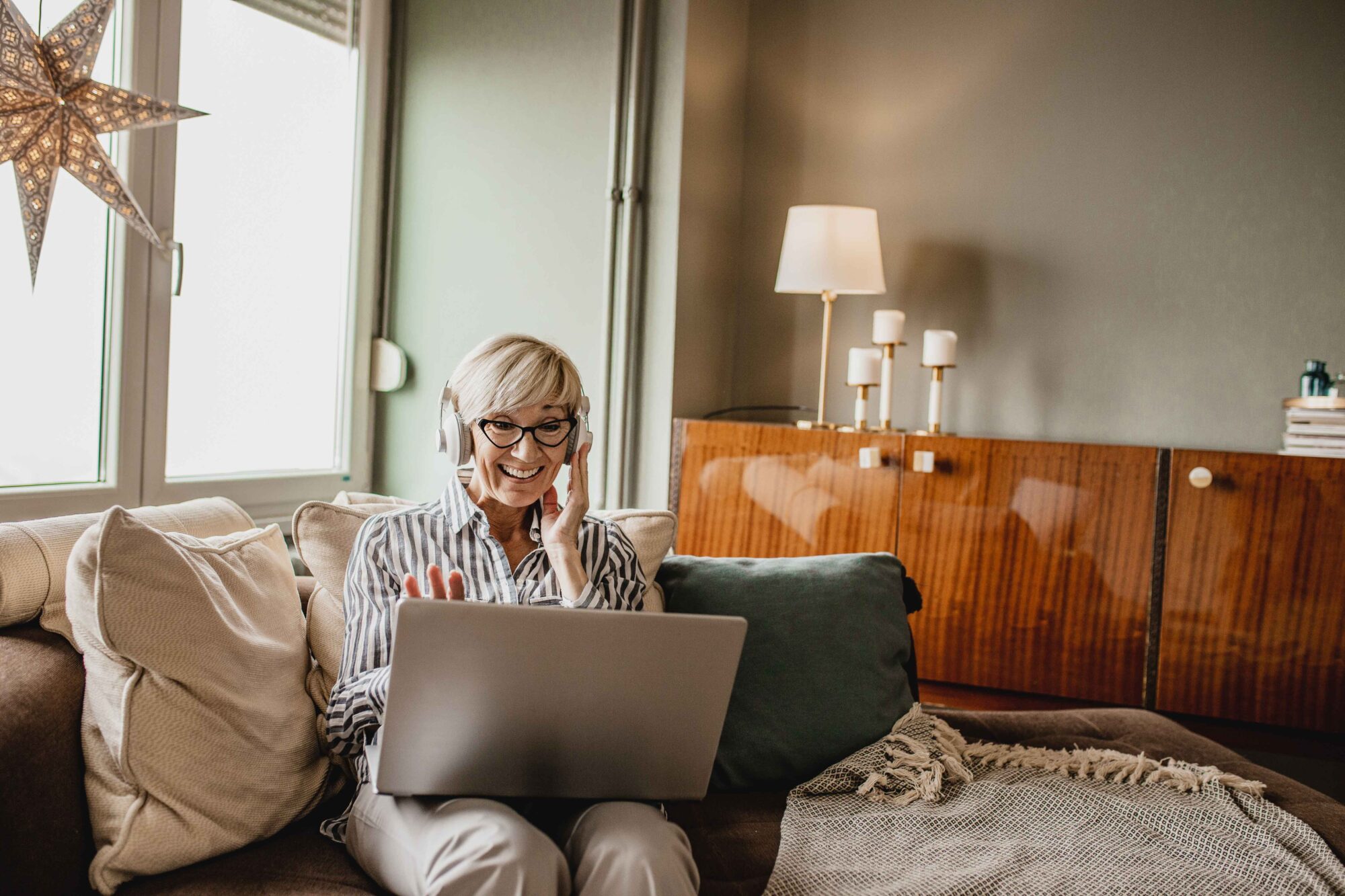 Mature woman is in her modern apartment using a laptop