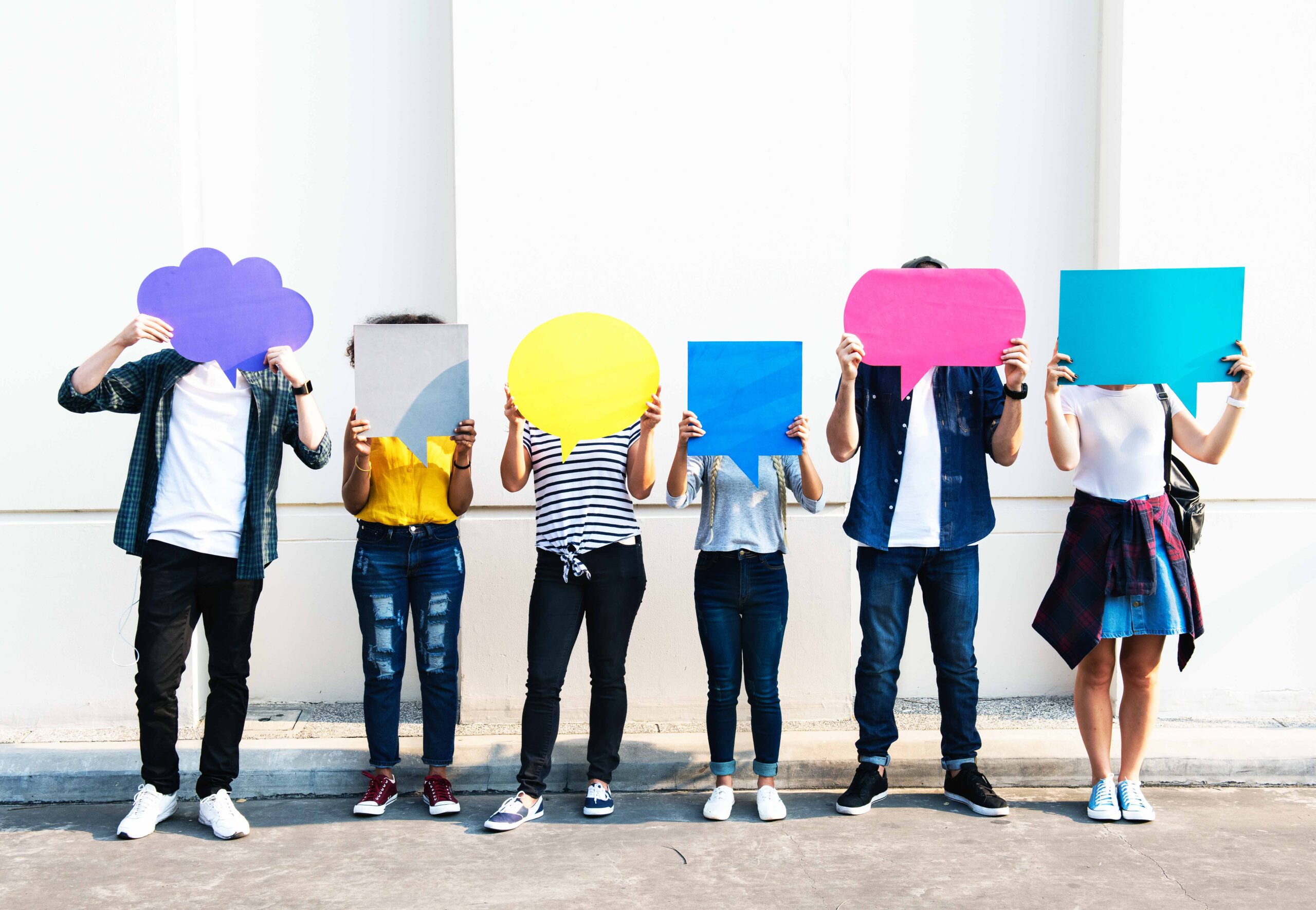 Photo: Young adult friends holding up copy space placard thought bubbles