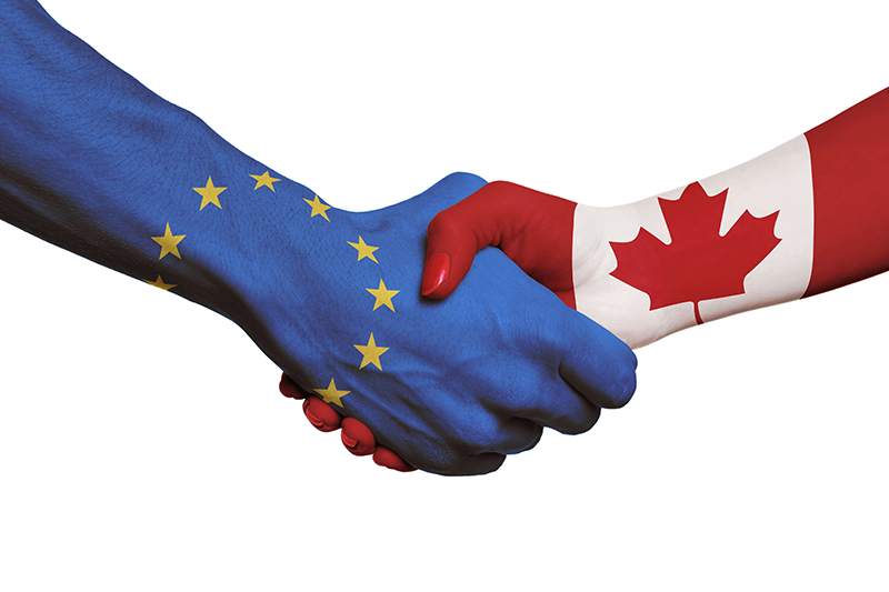 Hand mit EU Flagge und Hand mit Kanada Flagge