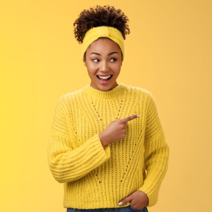 Astonished cute feminine modern african-american woman gossiping silly laughing drop jaw laughing surprised pointing right discuss during conversation interesting rumour place, yellow background