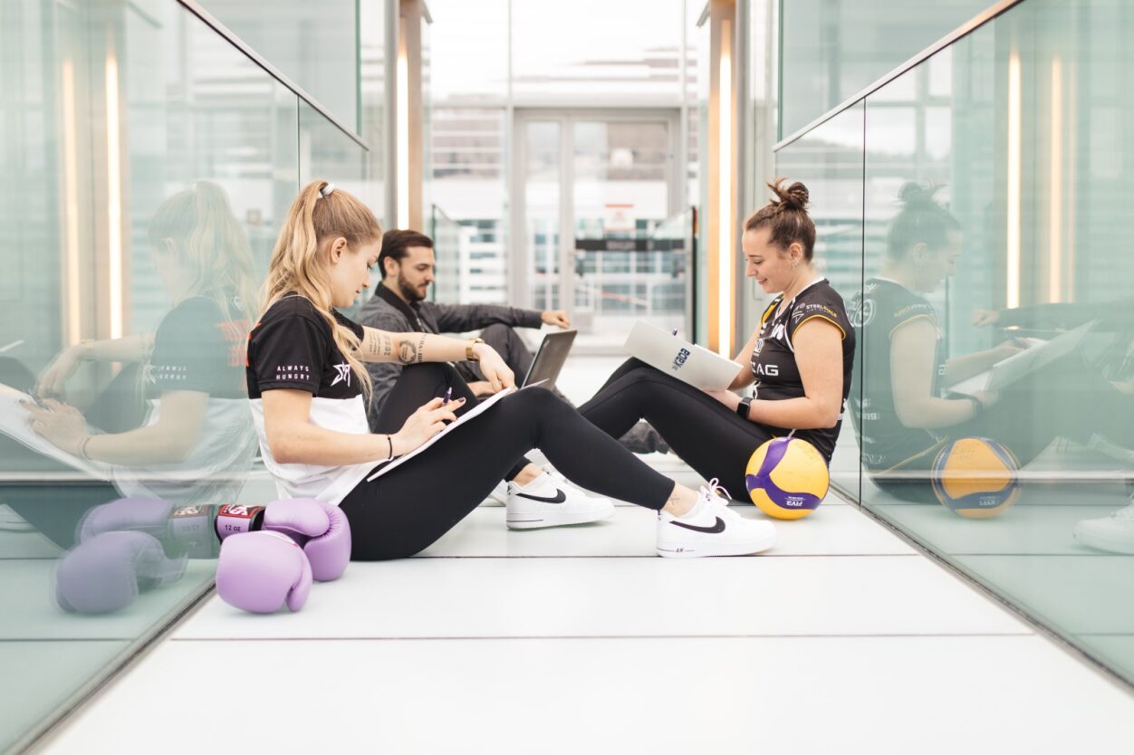 Sportler:innen sitzen mit Bällen am Boden