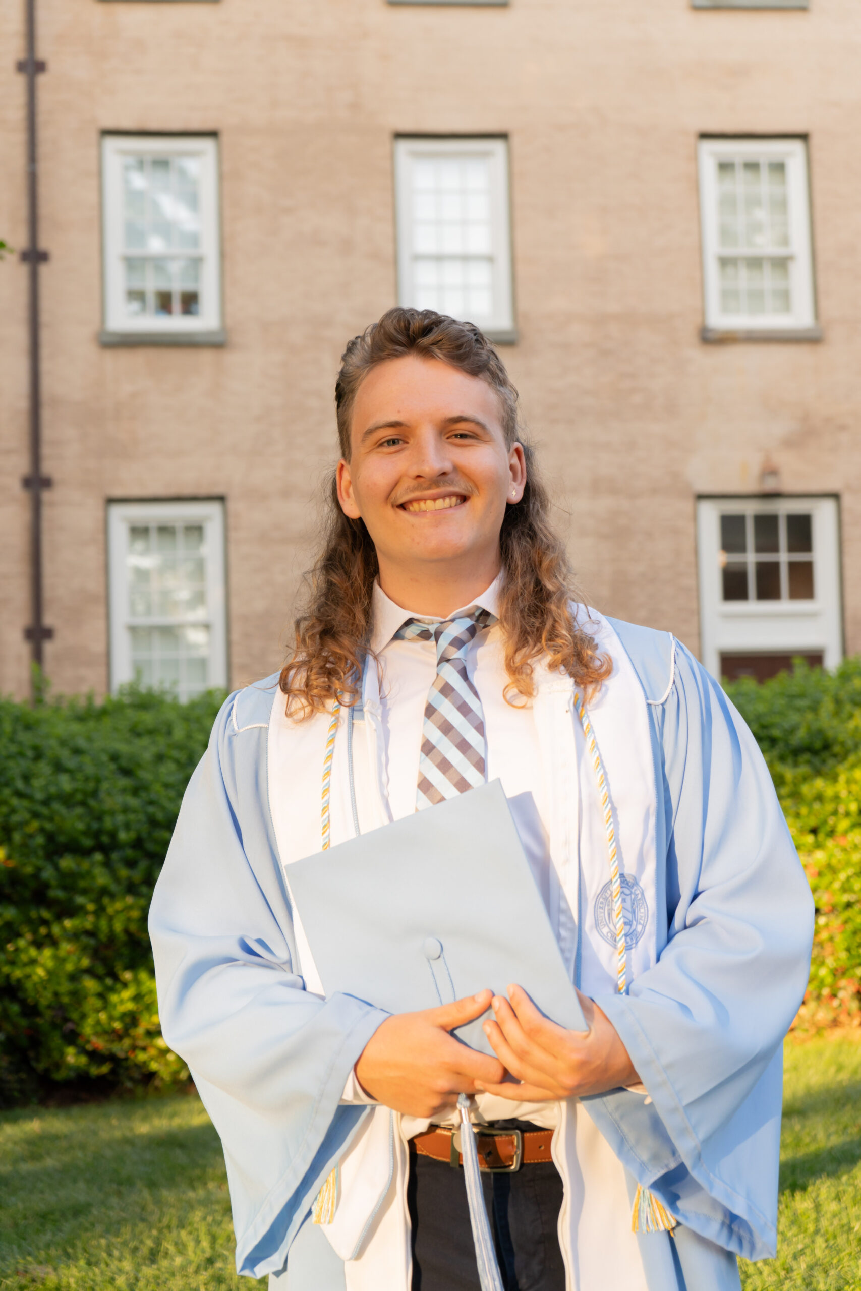 A portrait of Aidan Holland in graduation robes after graduating