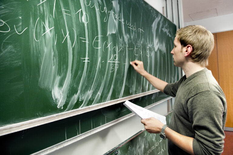 Lehrer schreibt an Tafel