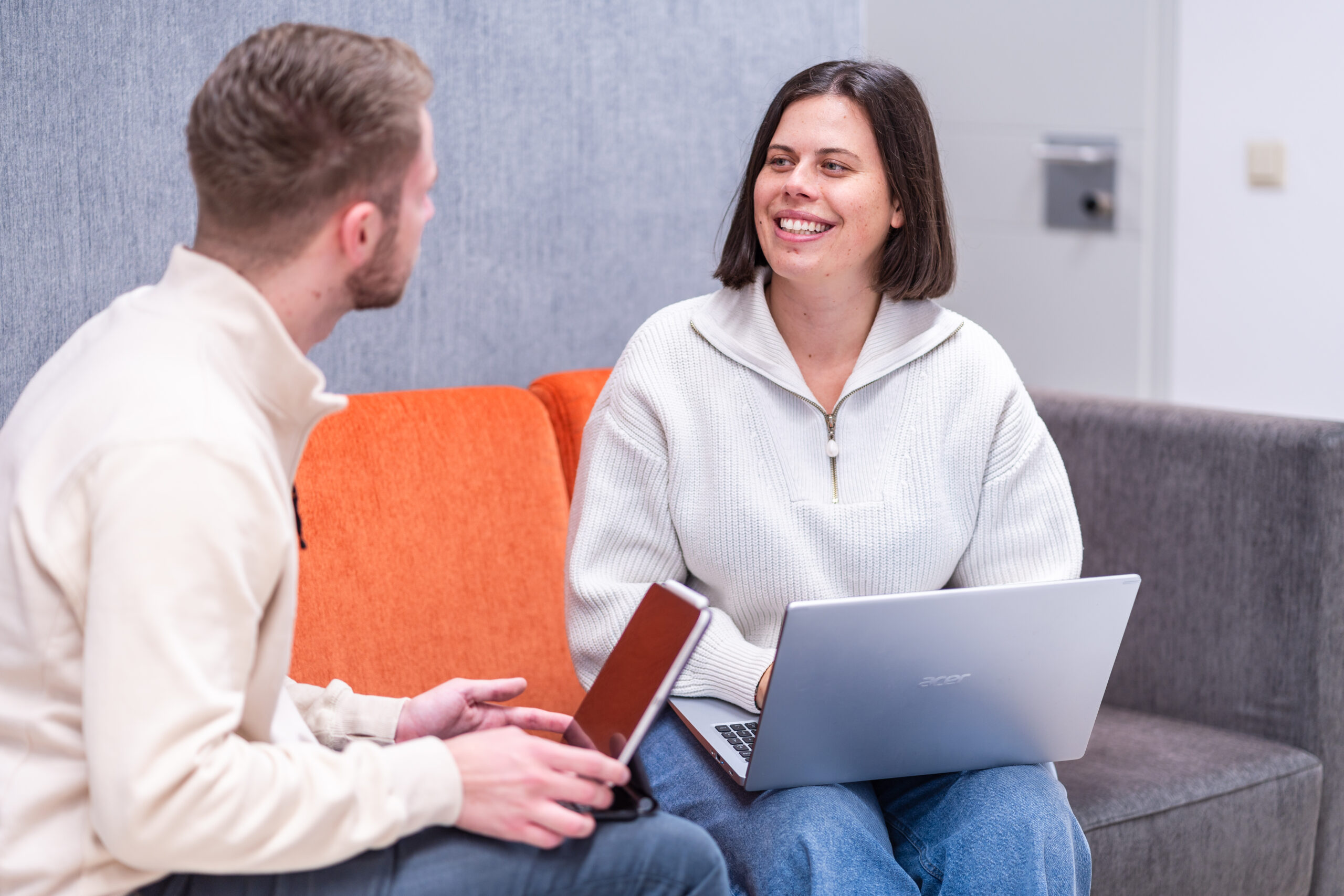 zwei Personen mit Laptops im Gespräch