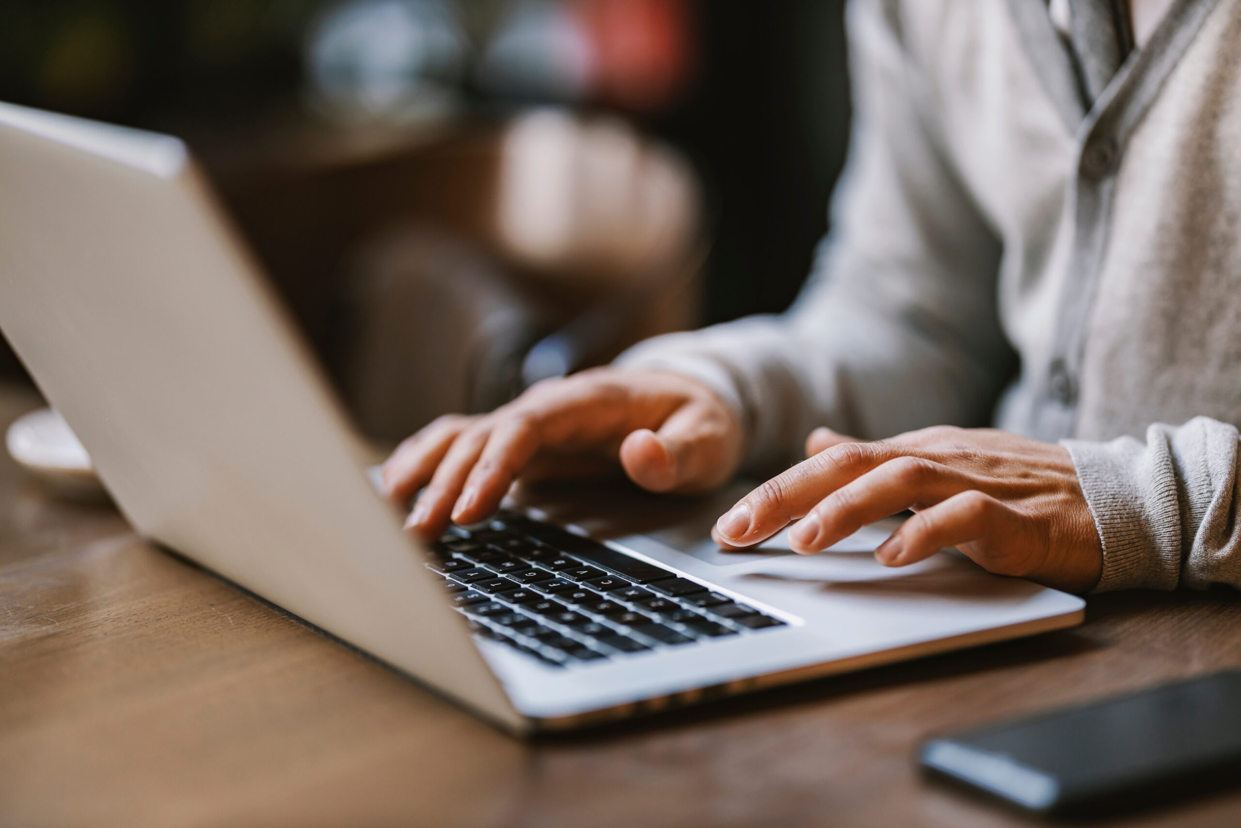 Close up of a young businessman typing a report on laptop from cafe.