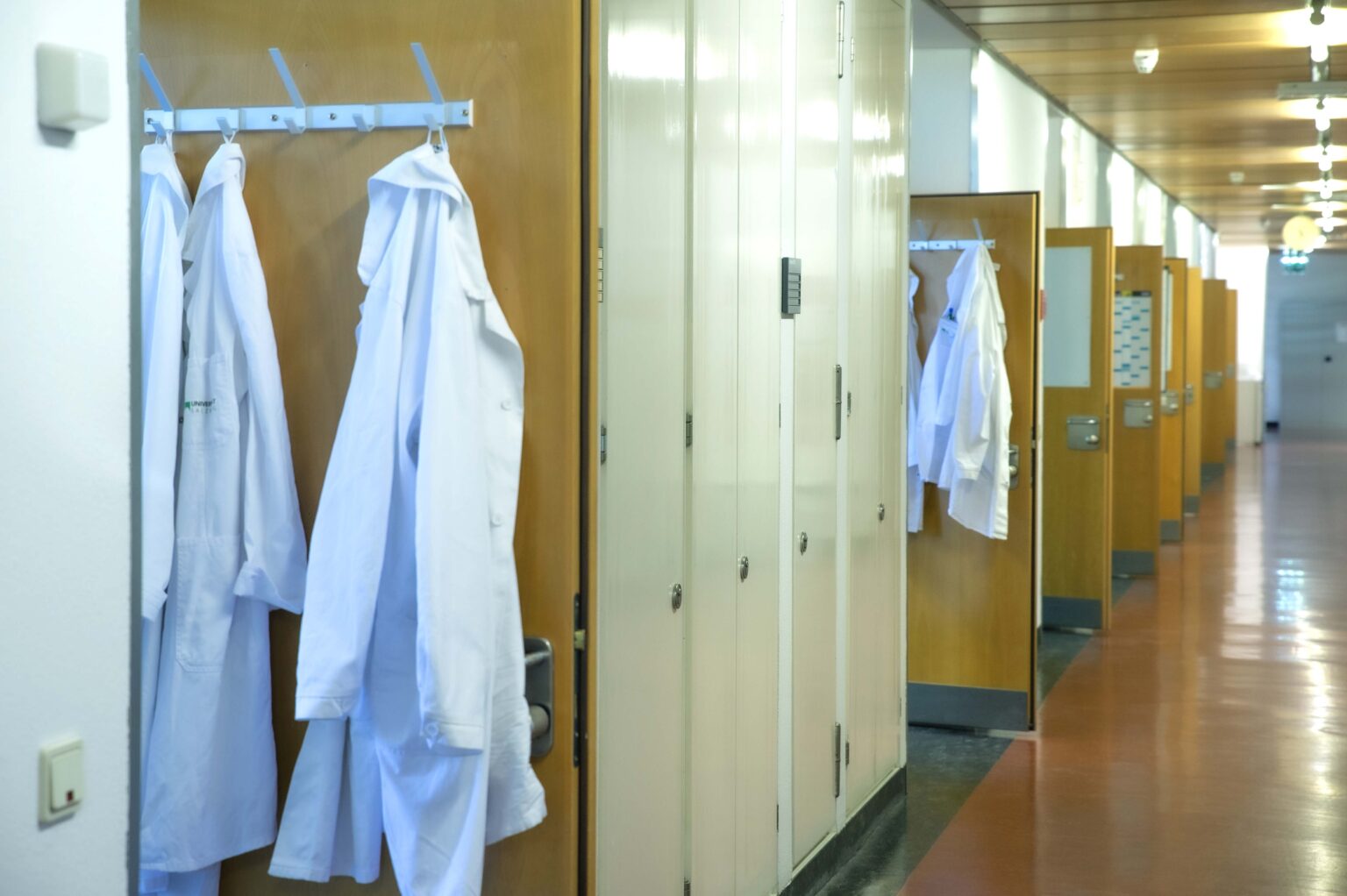 Lab coats down the hallway of PLUS facilities.