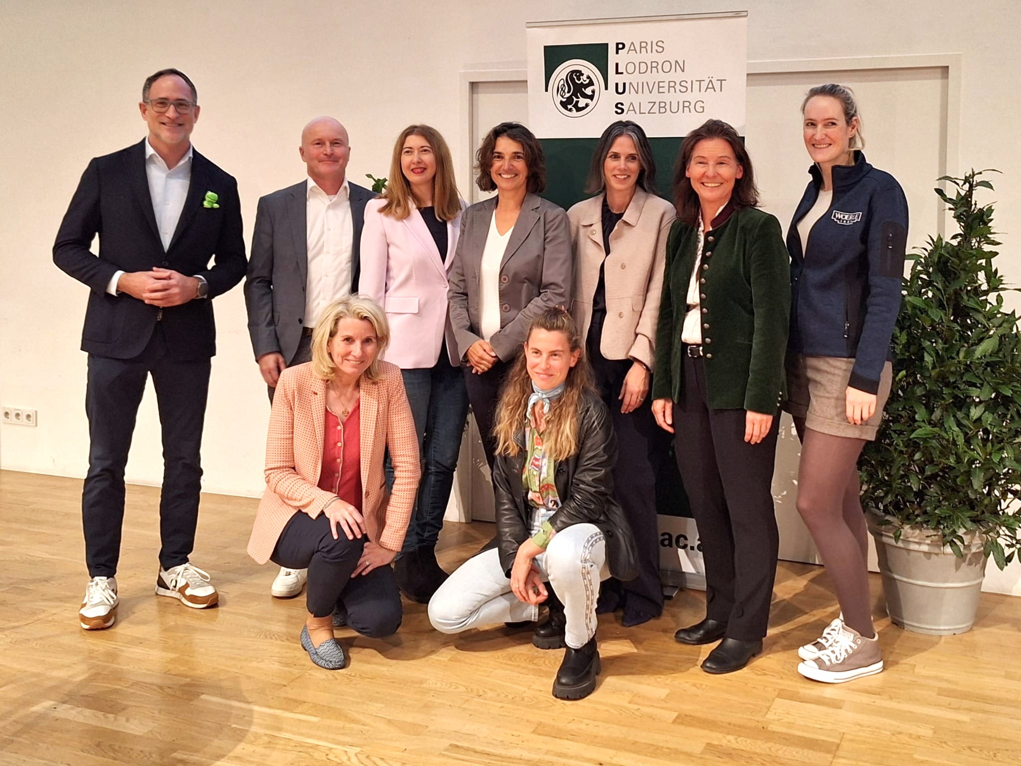 Eine Gruppe von Frauen und Männern vor einem Rollup mit dem Logo der Universität Salzburg.