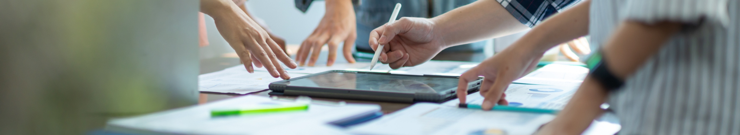 Personen stehen um Tisch und sprechen &uuml;ber Designentw&uuml;rfe