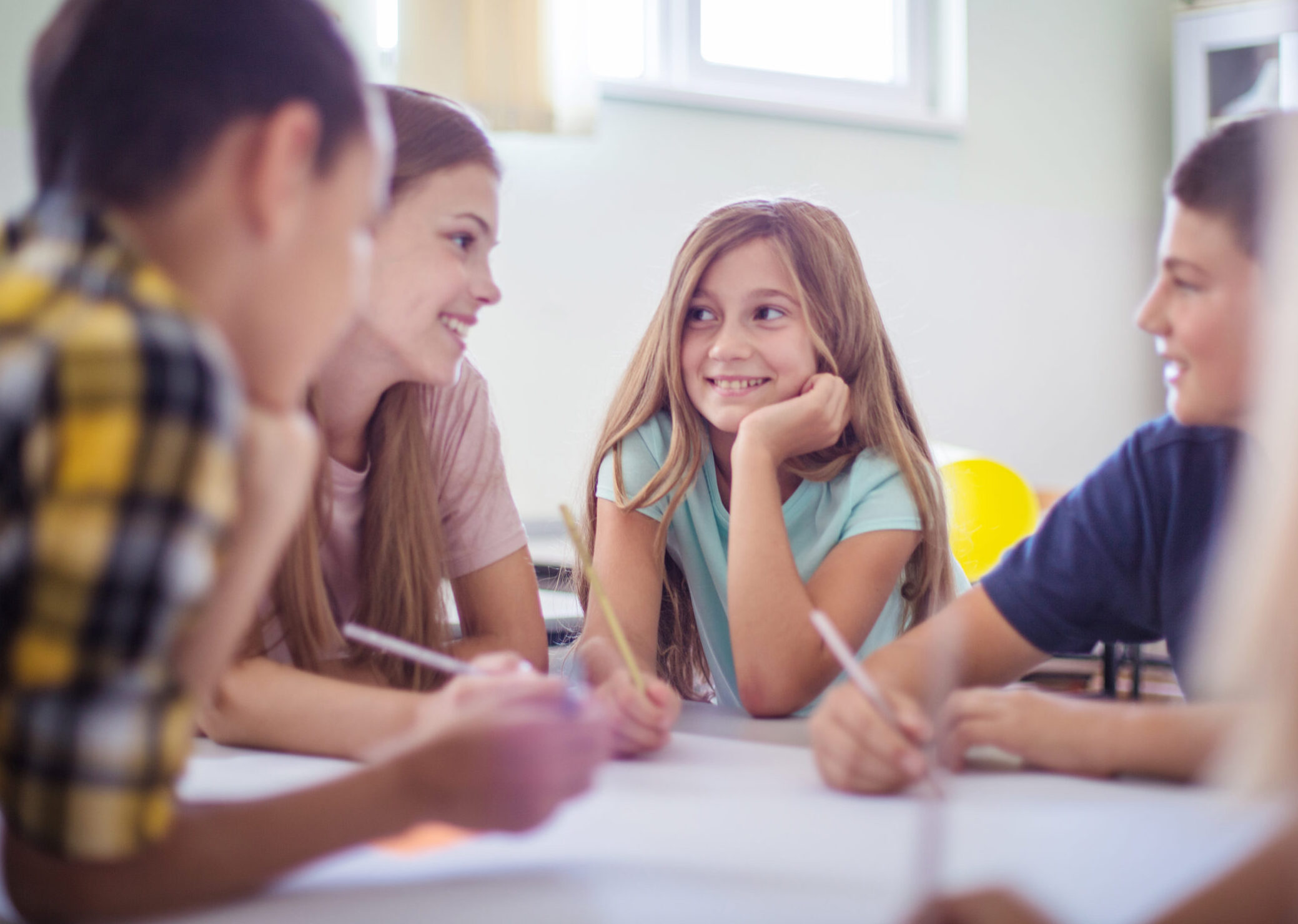 Kinder sitzen an einem Tisch und unterhalten sich.