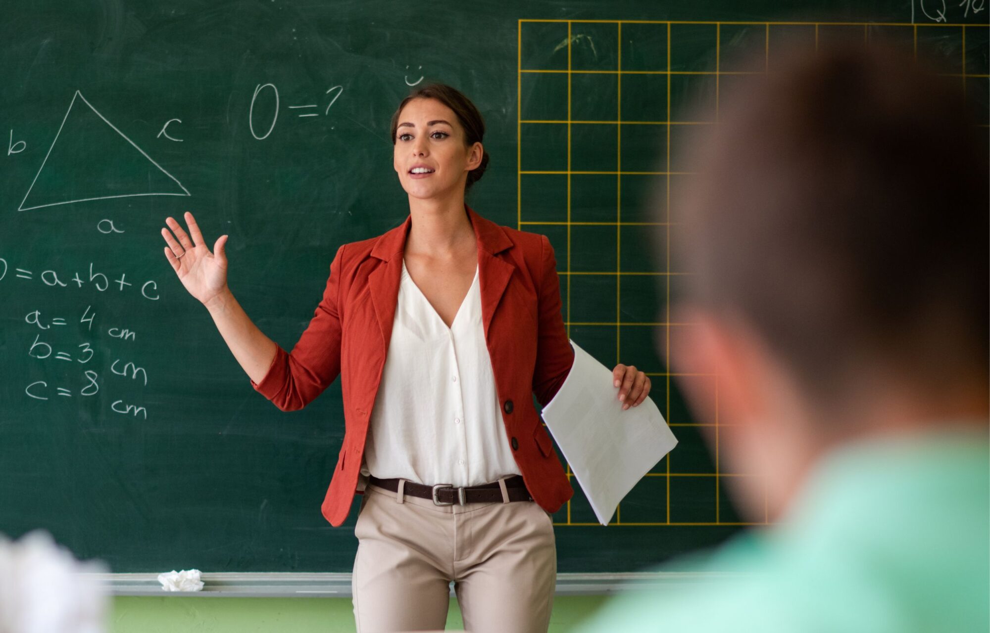 Lehrerin steht vor der Tafel und unterrichtet
