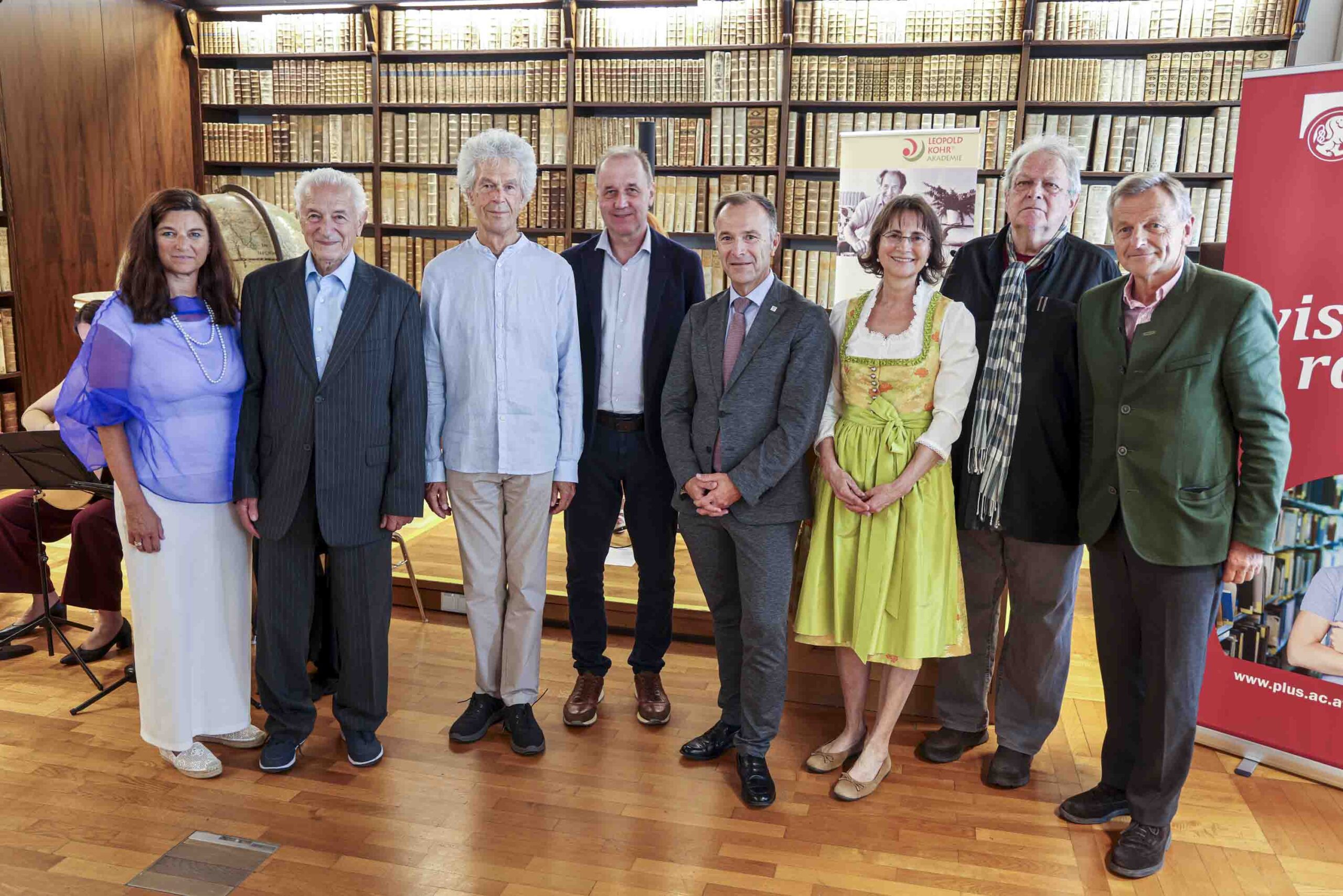Acht Menschen stehen vor einer Wand mit B&uuml;chern.