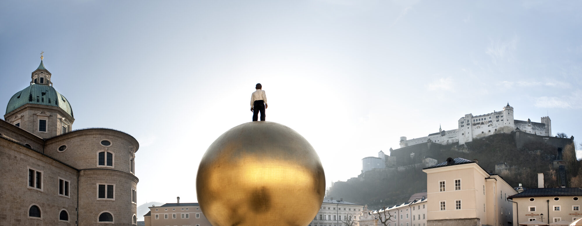 links Salzburger Dom, Mitte Mann auf Goldkugel, rechts Festung Hohensalzburg