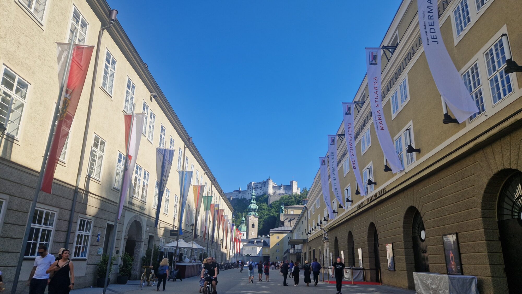 Blick in die Hofstallgasse mit dem Festspielbezirk, Fahnen und der Festung Hohen Salzburg.
