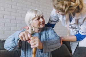 Pflegerin beugt sich über zu pflegende Frau
